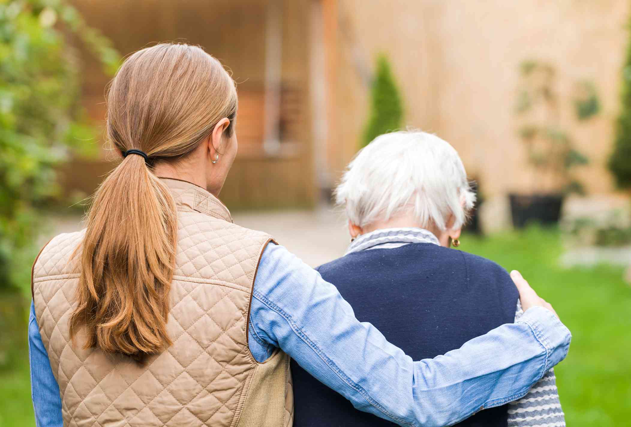 A woman walks with her arm around her loved one with dementia.