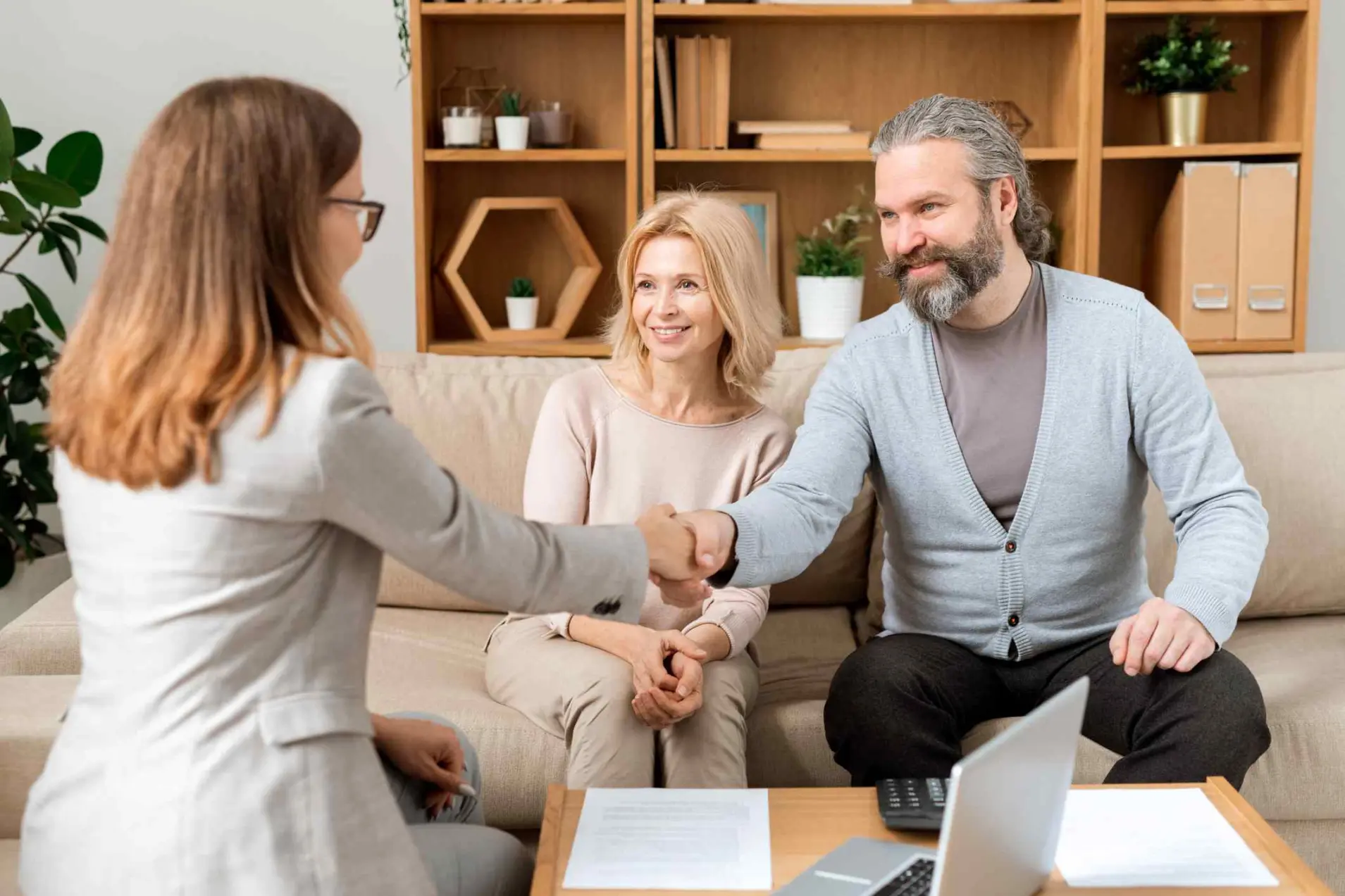 Happy mature bearded man giving hand to young real estate advisor after negotiating and signing all necessary papers