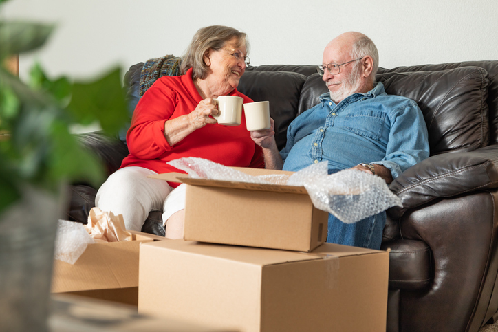 Tired Senior Adult Couple Resting on Couch with Cups of Coffee Surrounded with Moving Boxes Tired Senior Adult Couple Resting on Couch with Cups of Coffee Surrounded with Moving Boxes.