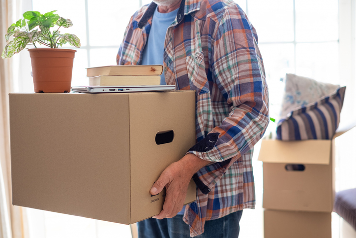 Smiling handsome senior man holding cardboard box posing in new house in moving day, concept of relocating, buying, renting house apartment Smiling handsome senior man holding cardboard box posing in new house in moving day, concept of relocating, buying, renting house apartment