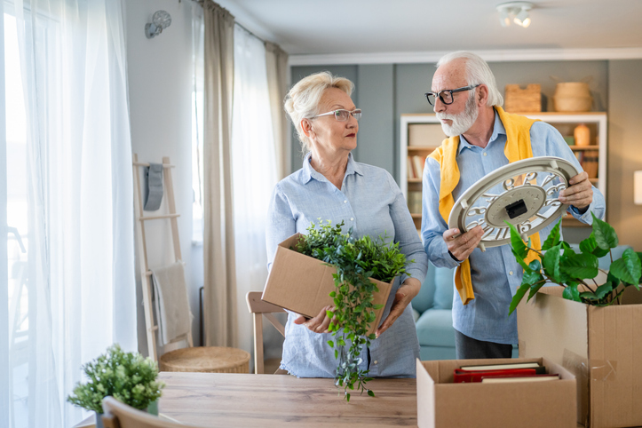 Senior couple man and woman husband wife pack or unpack boxes moving family senior couple man woman husband and wife pensioner grandfather grandmother moving in new apartment taking their stuff belongings and plants in or out of boxes packing or unpacking real people
