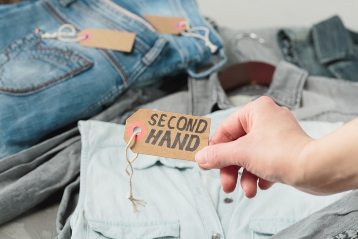 A denim jacket with a “secondhand” label at a thrift store.