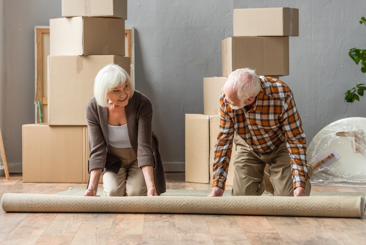 iStock-1280672469 A couple rolling up their rug on the floor.