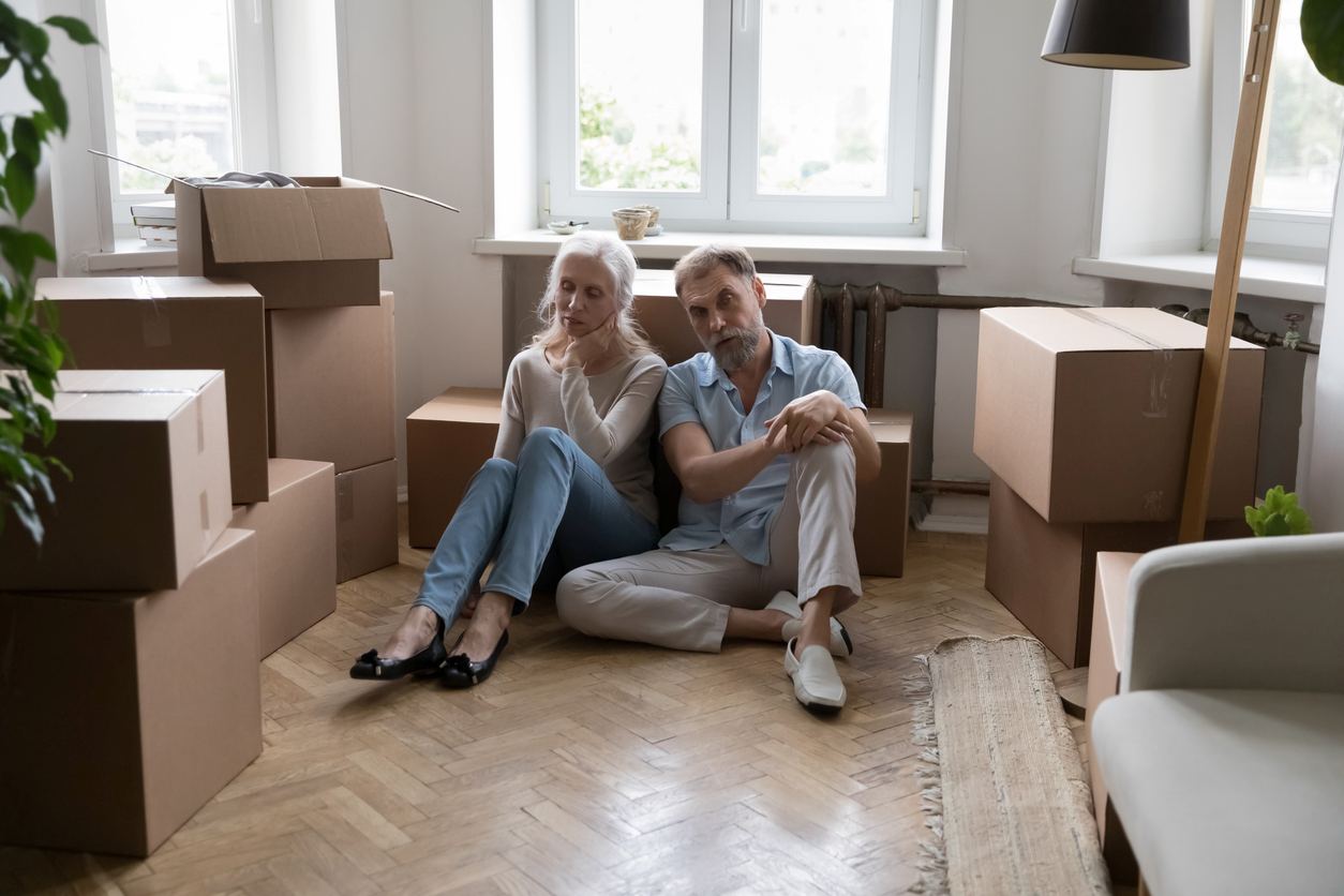 iStock-1400788390 A couple sitting on the floor around all of their cluttered boxes.
