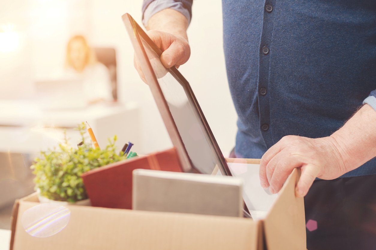 A man putting a picture frame into a moving box.