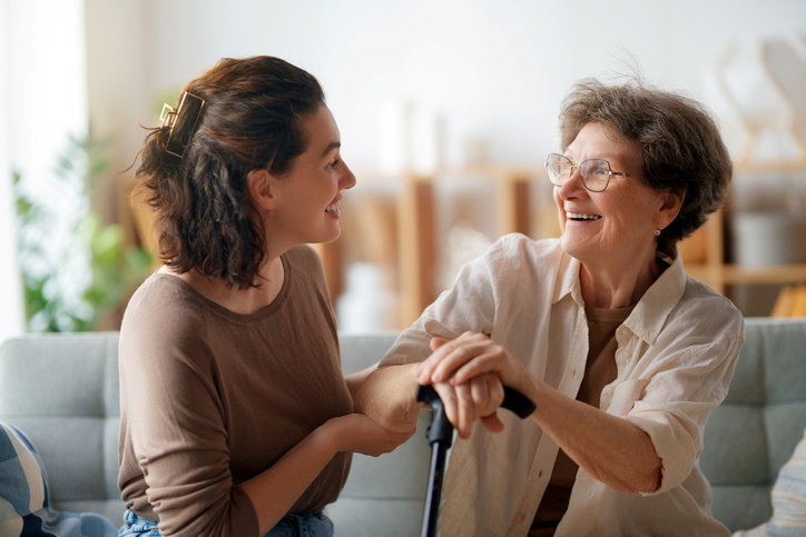 A daughter and her senior mom are having a conversation on the couch.