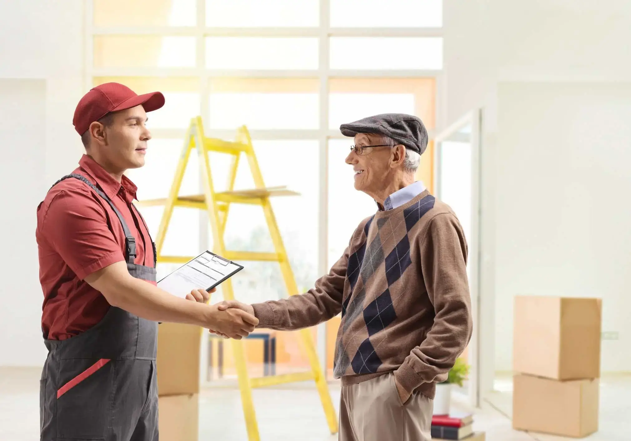 Mover shaking hands with a senior man inside a house
