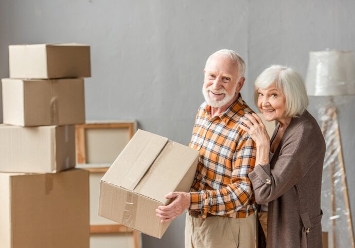 iStock-1280672470 An older couple moving cardboard boxes.