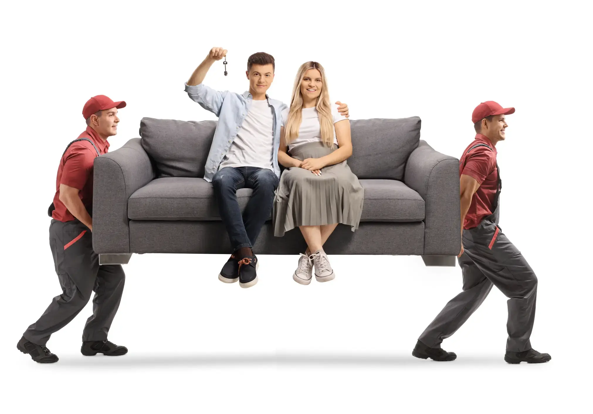 Movers carrying a young couple sitting on a gray sofa and holding a house key isolated on white background