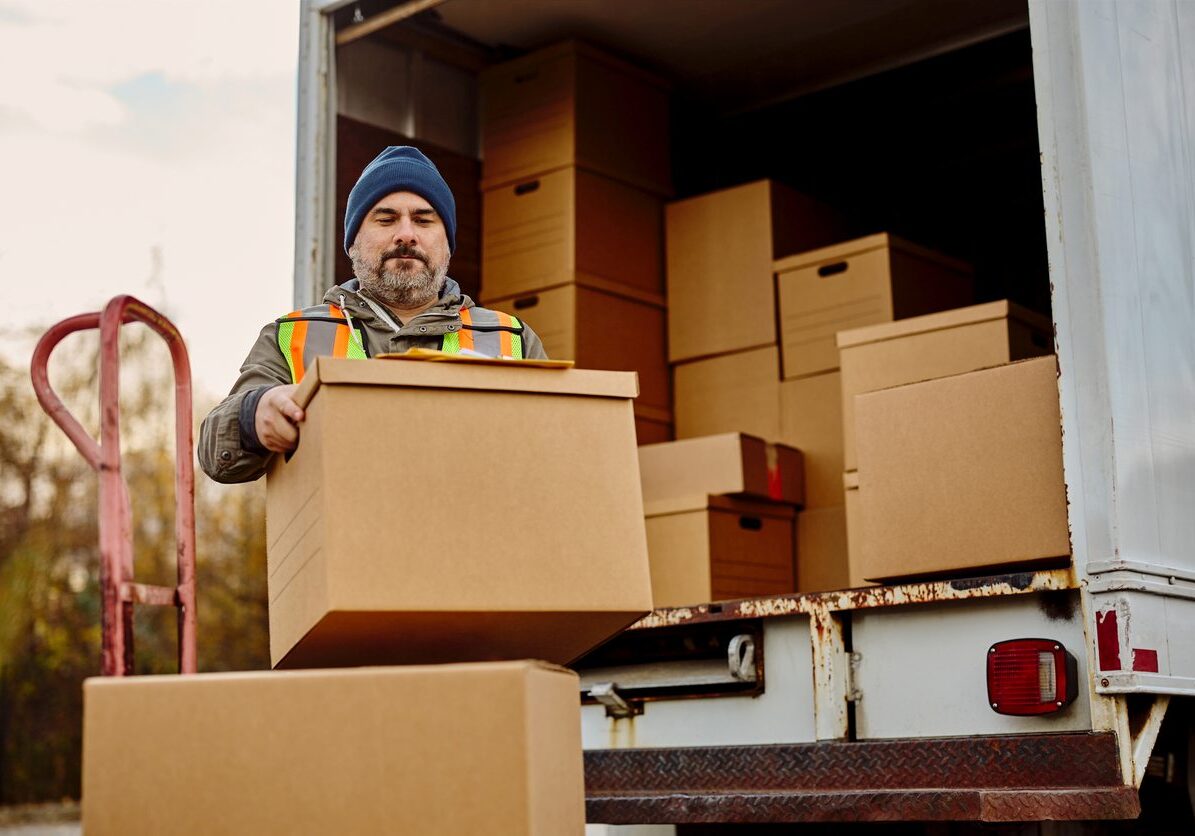 Mover in a beanie unloads boxes onto a dolly.
