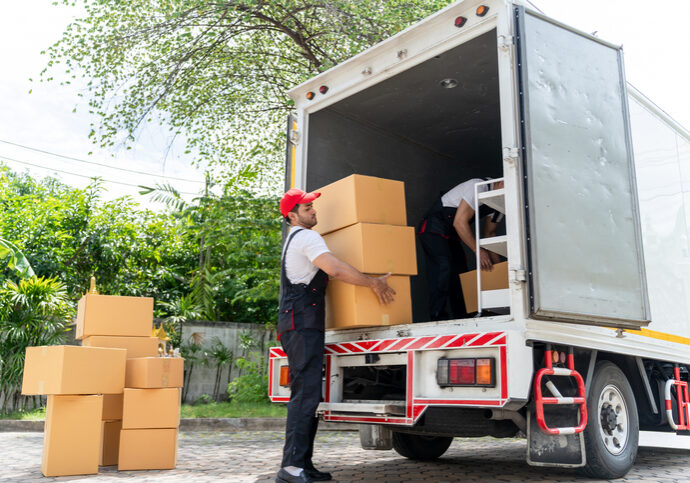Caucasian young delivery man delivering package to customer at home. Attractive courier postman worker working and loading deliver a box cardboard postal from car truck infront of the house. Caucasian young delivery man delivering package to customer at home. Attractive courier postman worker working and loading deliver a box cardboard postal from car truck infront of the house.