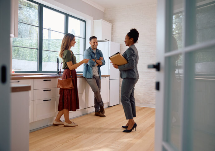 Happy black real estate agent and a couple in the kitchen of a new house. Happy couple talking with real estate agent while buying new home.