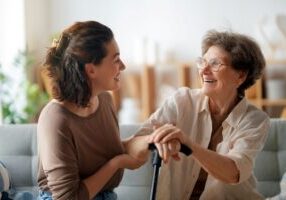 A daughter and her senior mom are having a conversation on the couch.