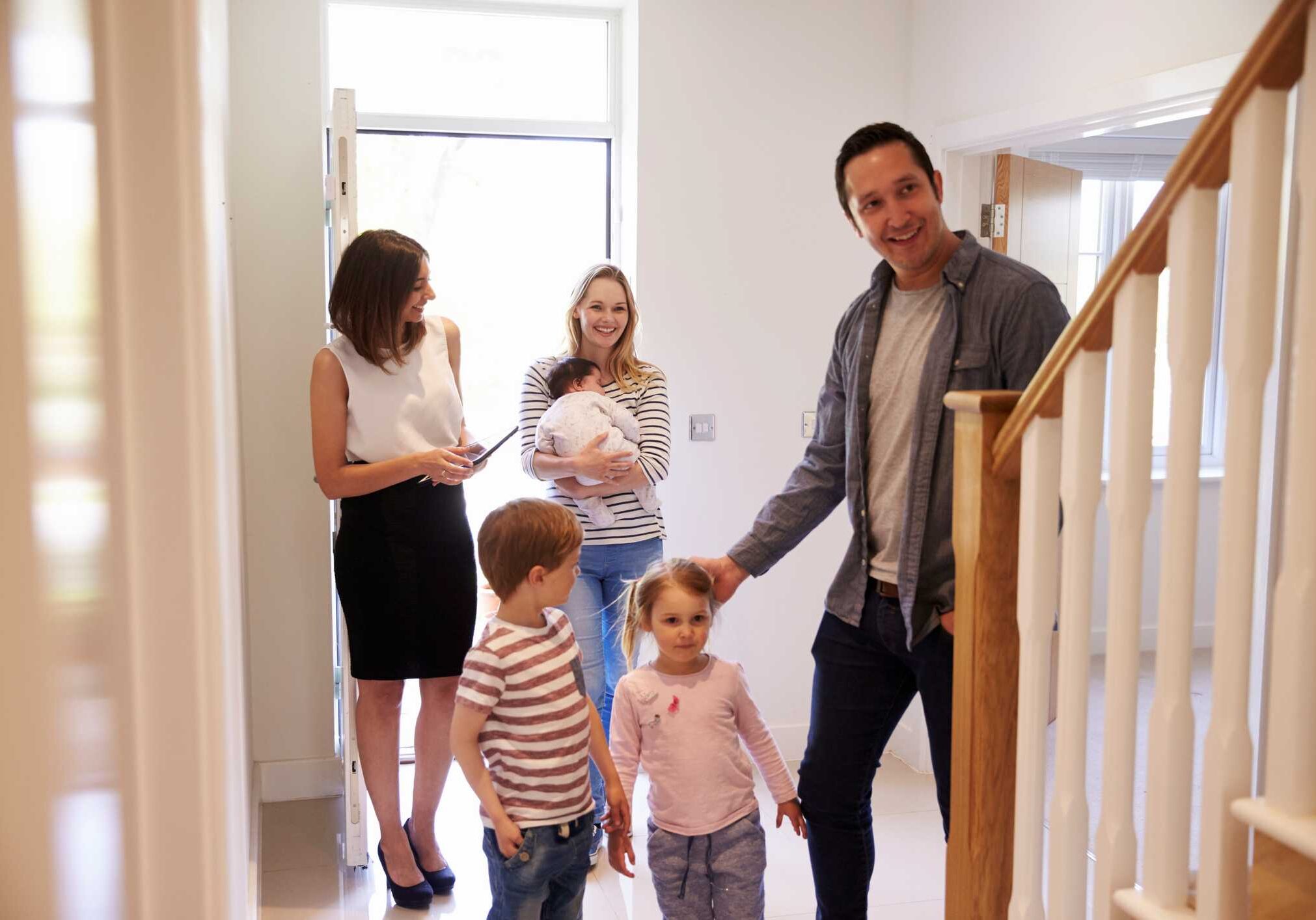 iStock-546201674 Real Estate Agent Showing Young Family Around Property For Sale