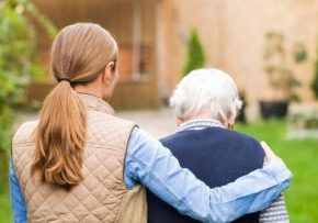 A woman walks with her arm around her loved one with dementia.