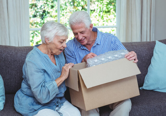 Smiling senior couple looking inside cardboard box at home