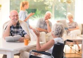 A group of seniors sits together happily in a senior living community.