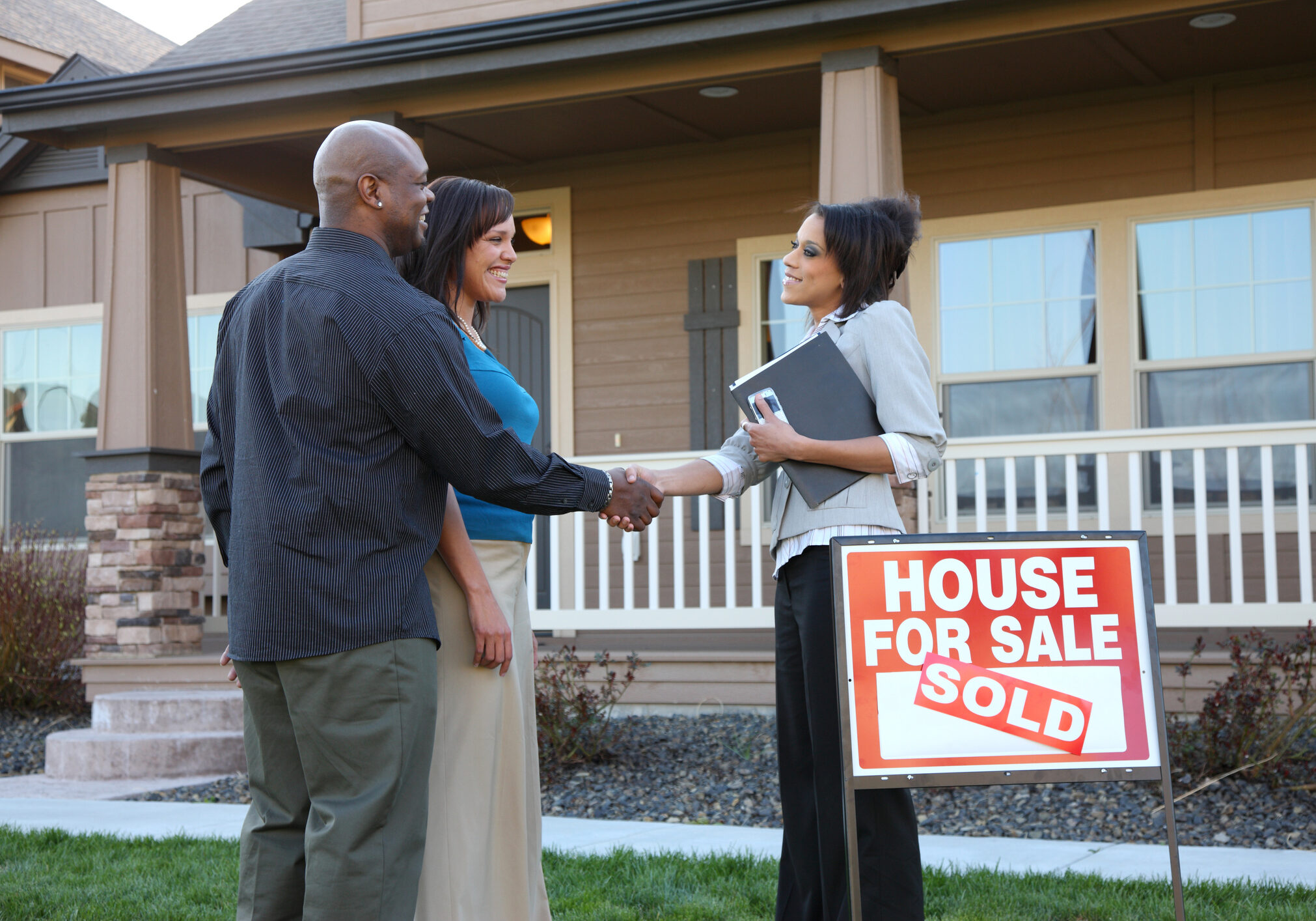 Couple shakes hands with Real Estate Agent outside new house Couple shakes hands with Real Estate Agent outside new house