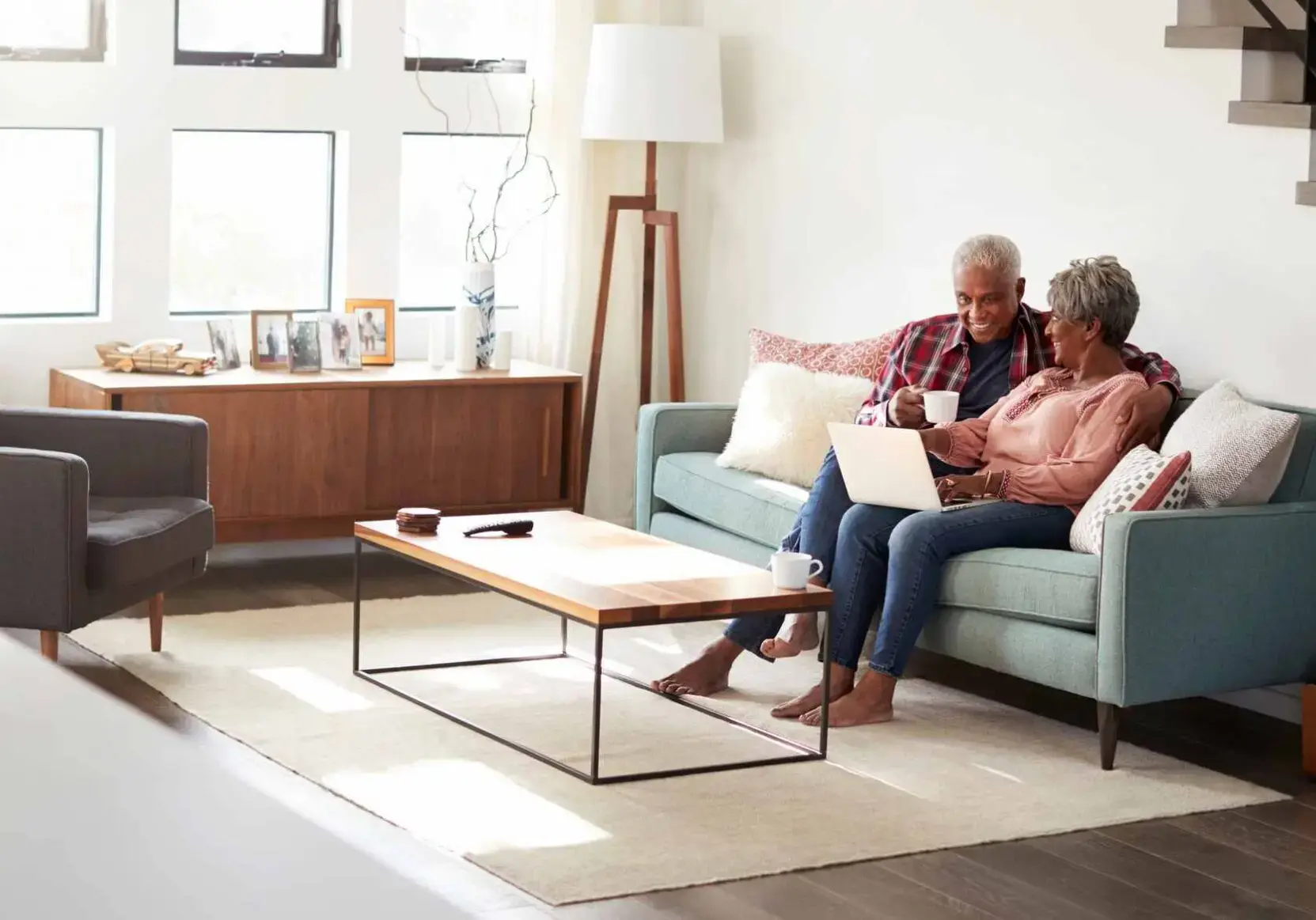 iStock-992096396 Senior Couple Sitting On Sofa At Home Using Laptop To Shop Online