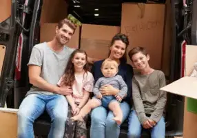 A family sits together in their car before starting their cross-country move.